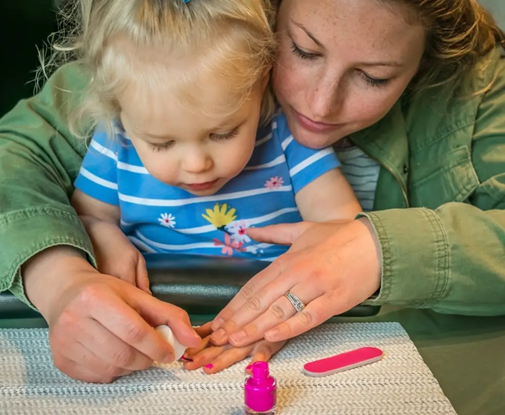 mother painting her young daughter’s fingernails