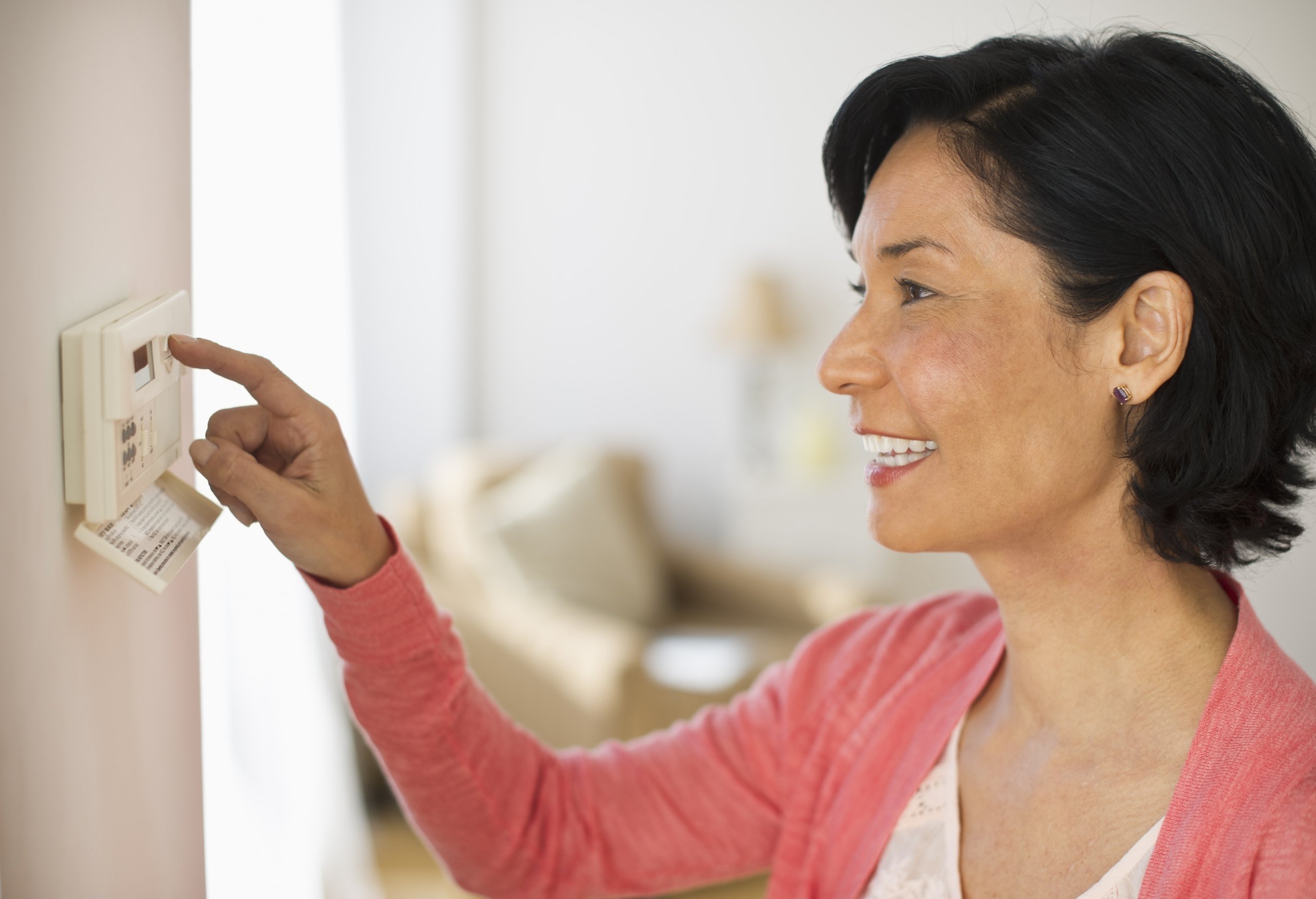 woman checking the thermostat in her home
