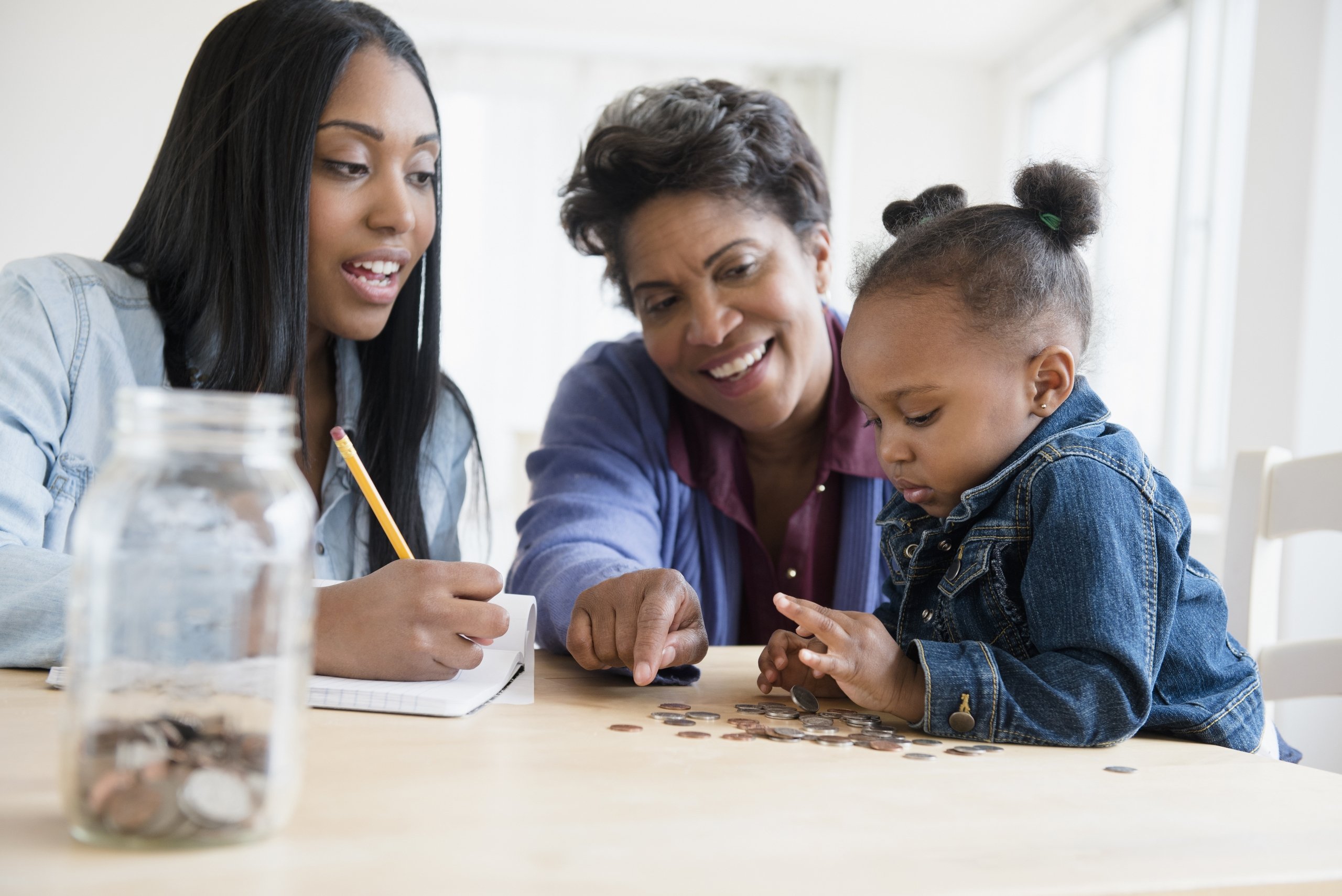mother and grandmother teaching young girl about managing money