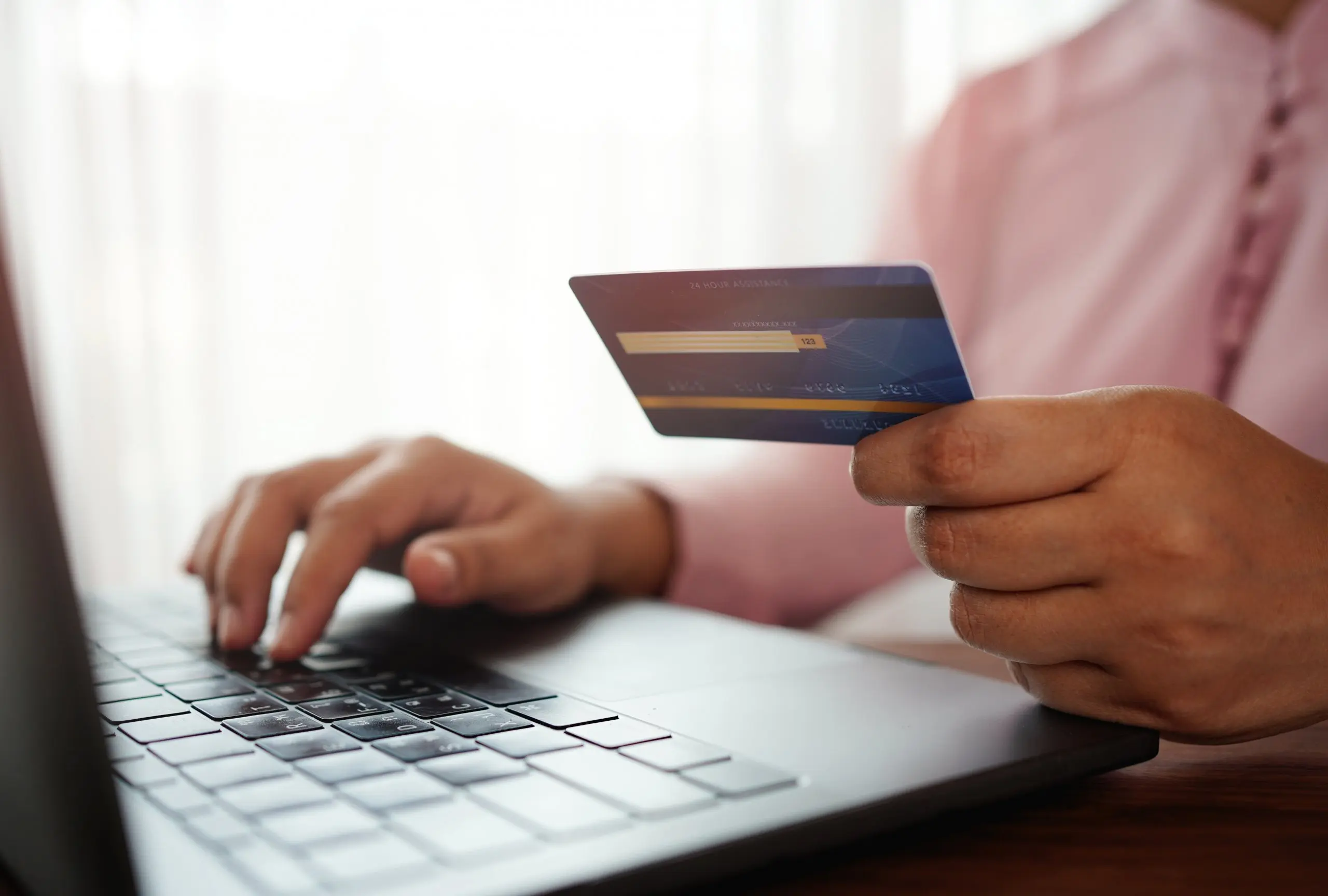 man holding a credit card while making an online purchase on a laptop