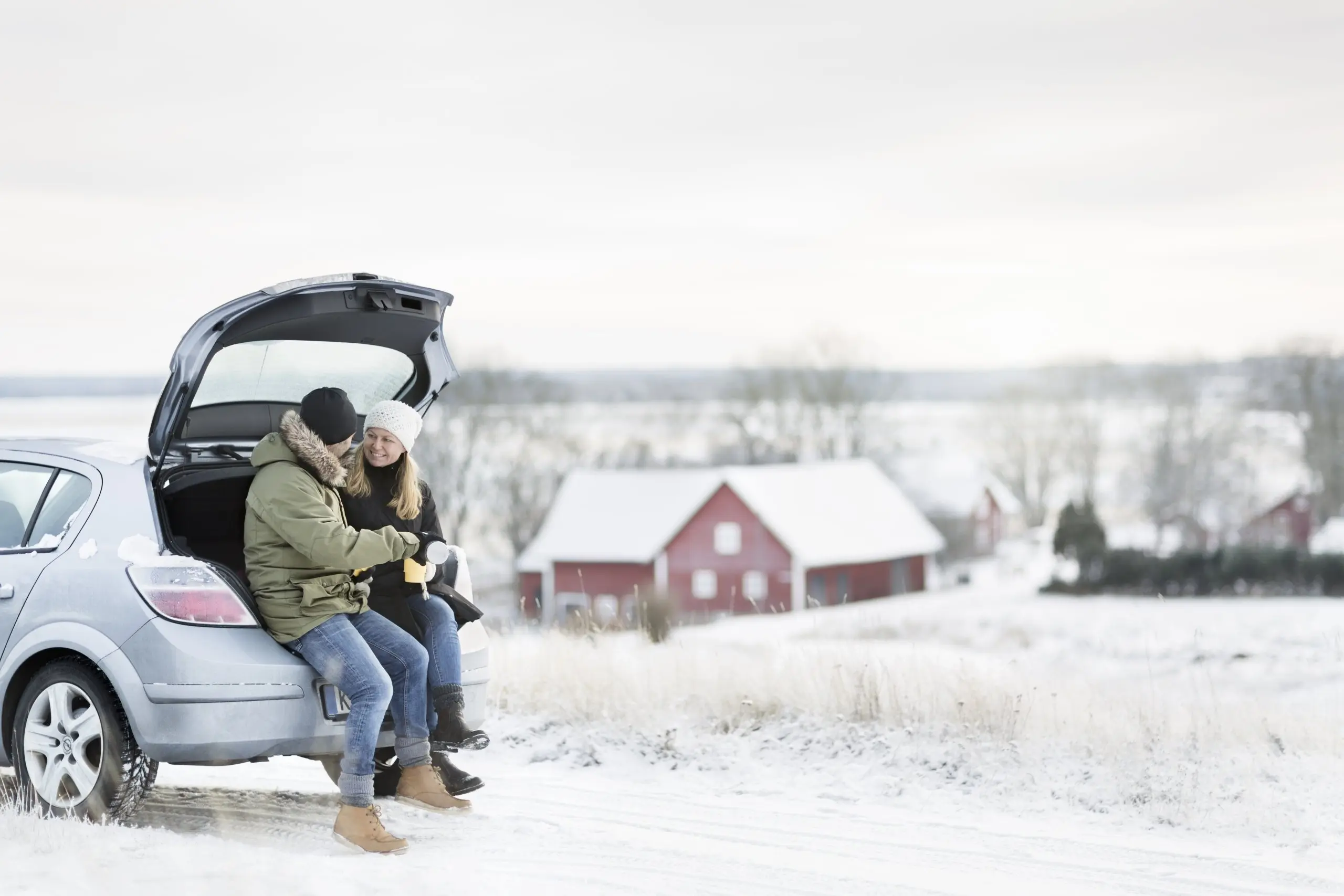 Couple sitting on the trunk of car during winter