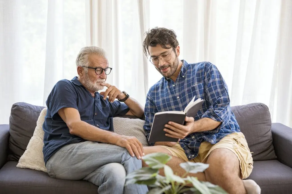 Older man and younger man sitting on sofa having a conversation