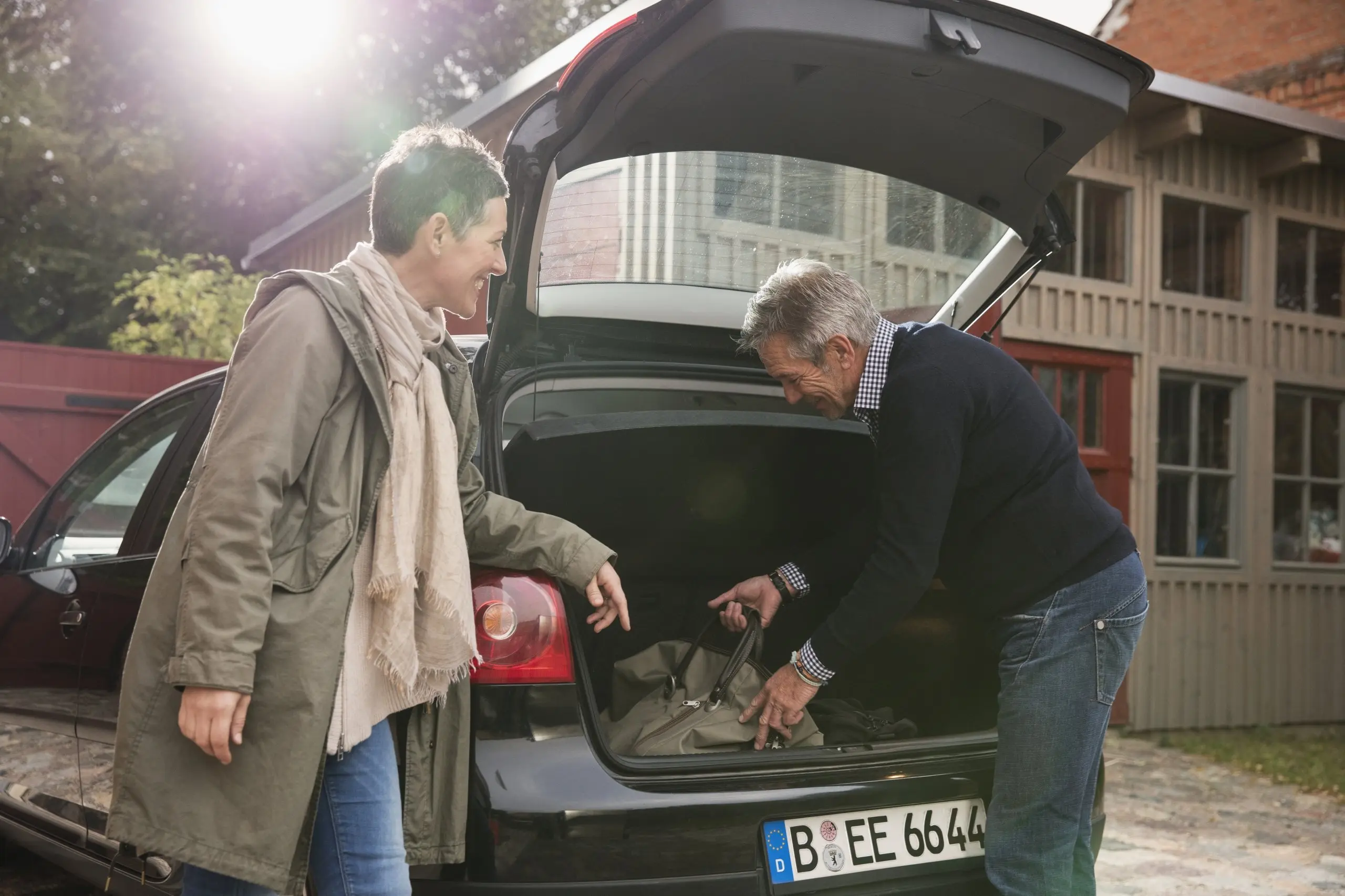 A couple reaching inside the trunk of their car