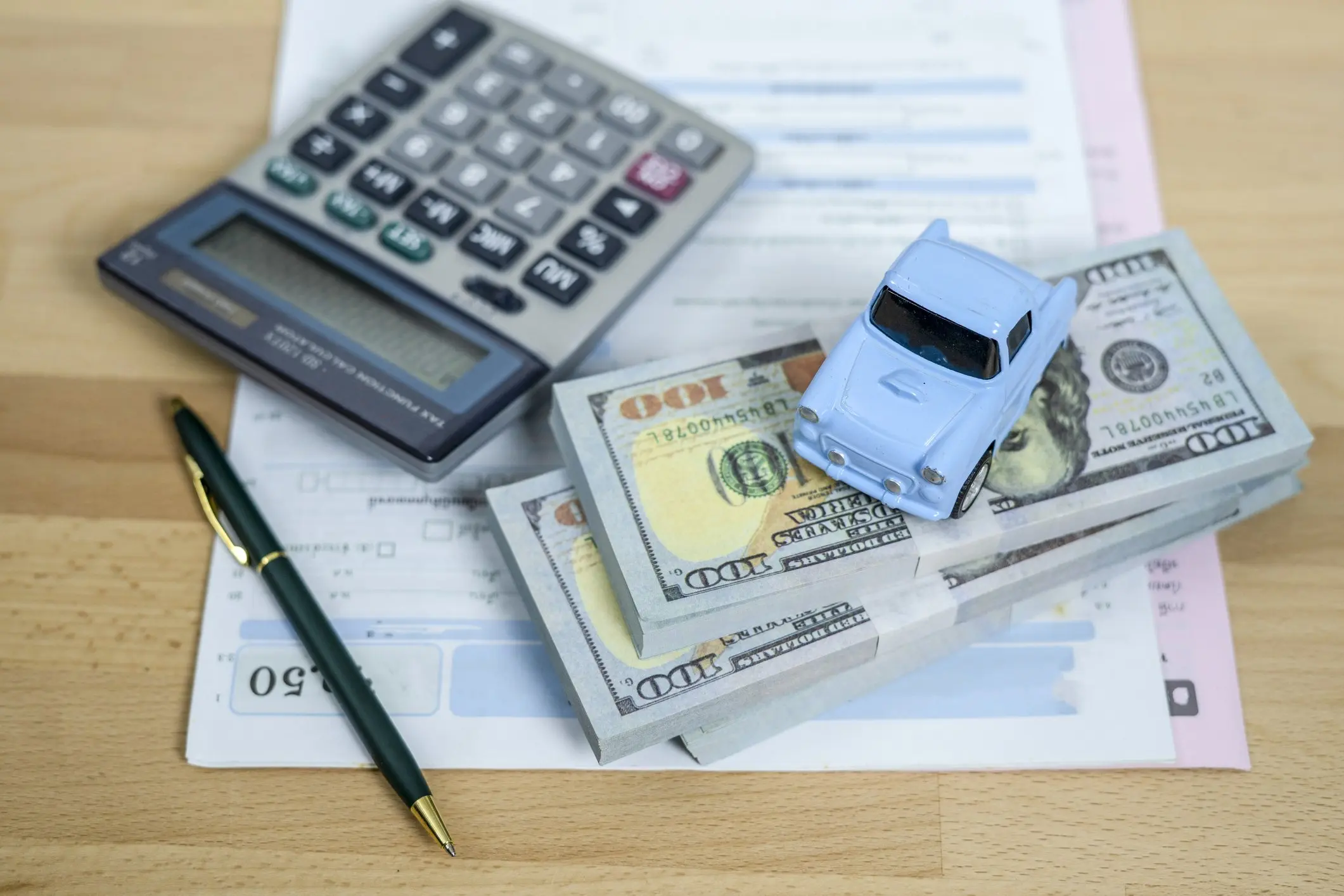 Calculator and stack of money to pay for car expenses