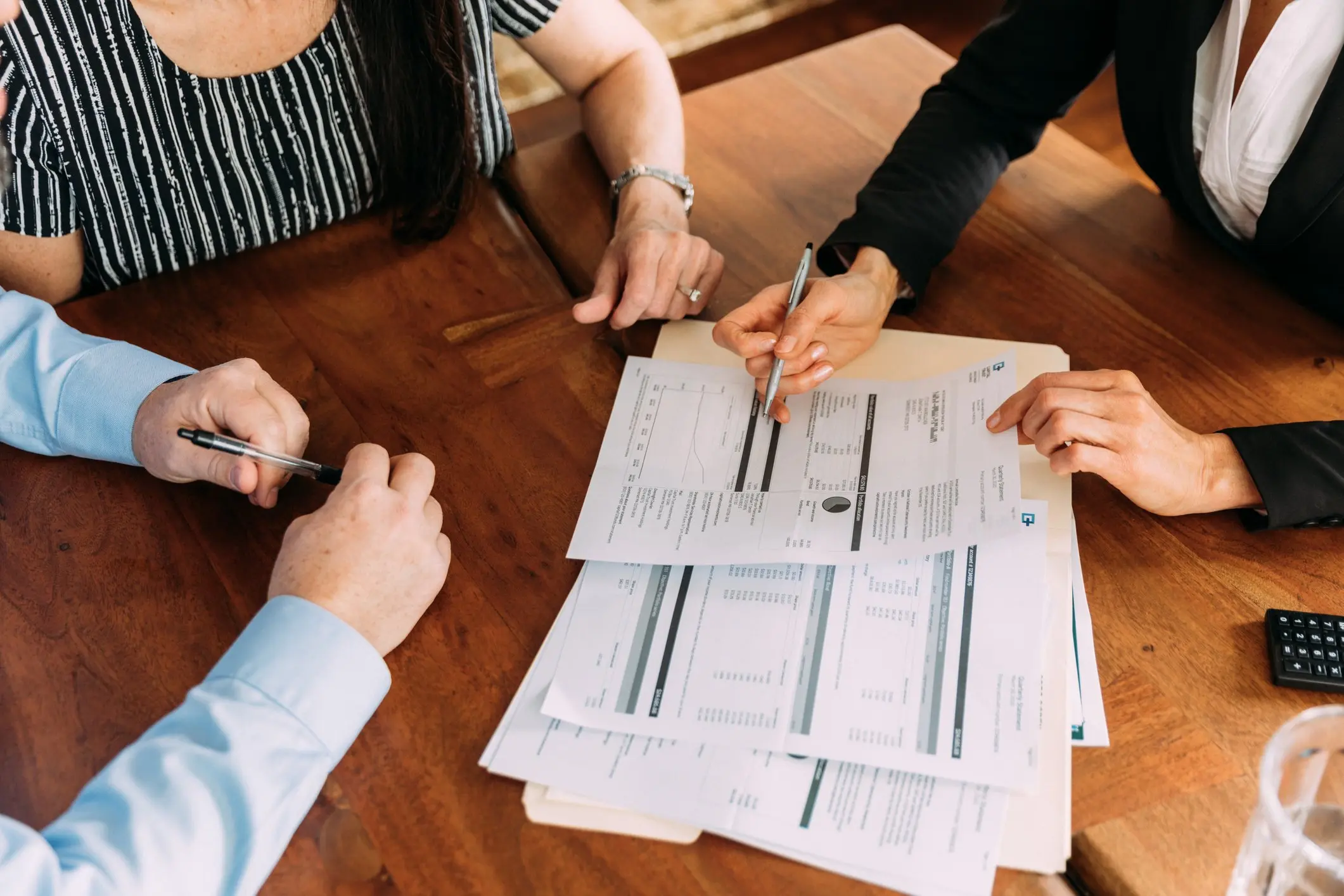 A group of people sitting at a table looking over paperwork for types of loans available to them.