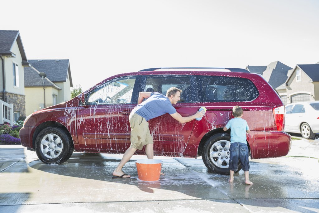 A father and son wash their family van, which is the type of collateral for an auto loan.