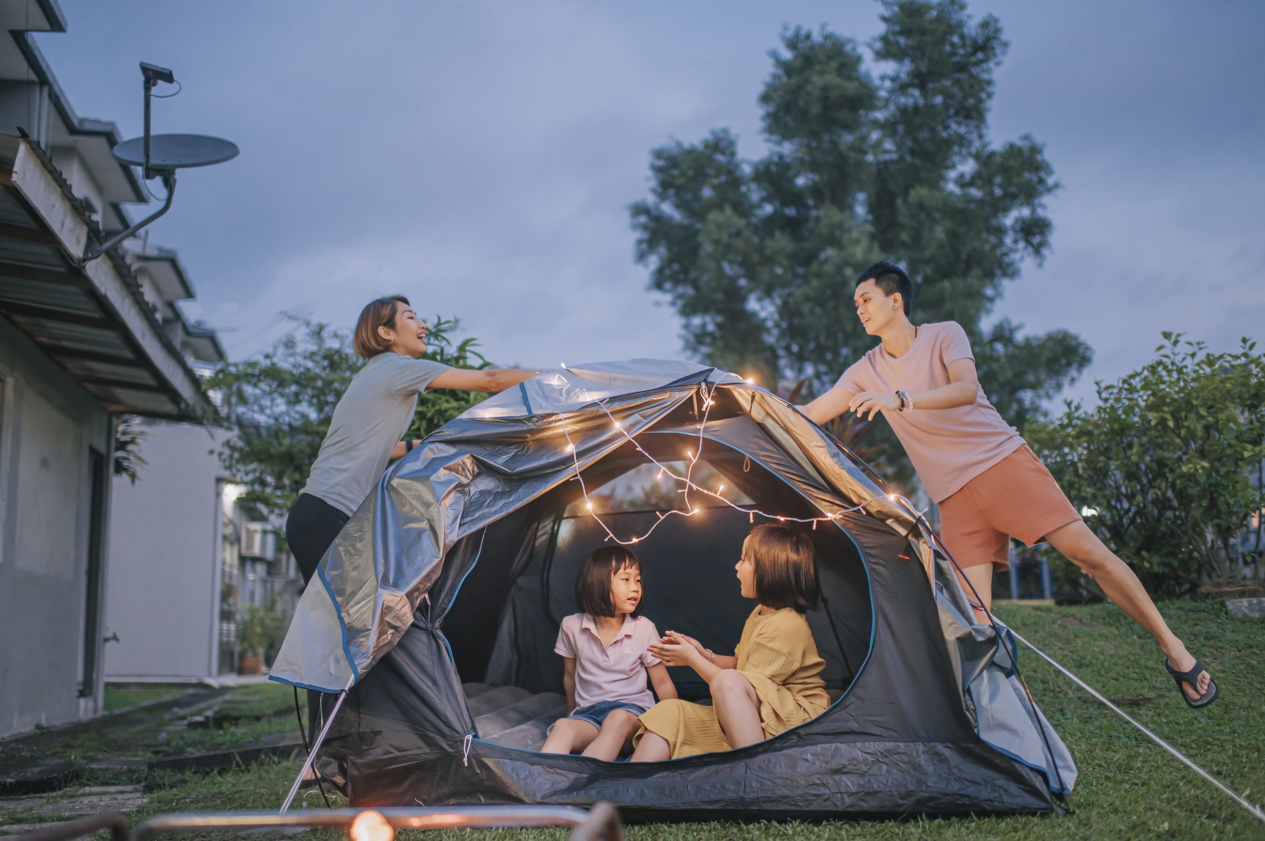 a family camping in the backyard during summertime 