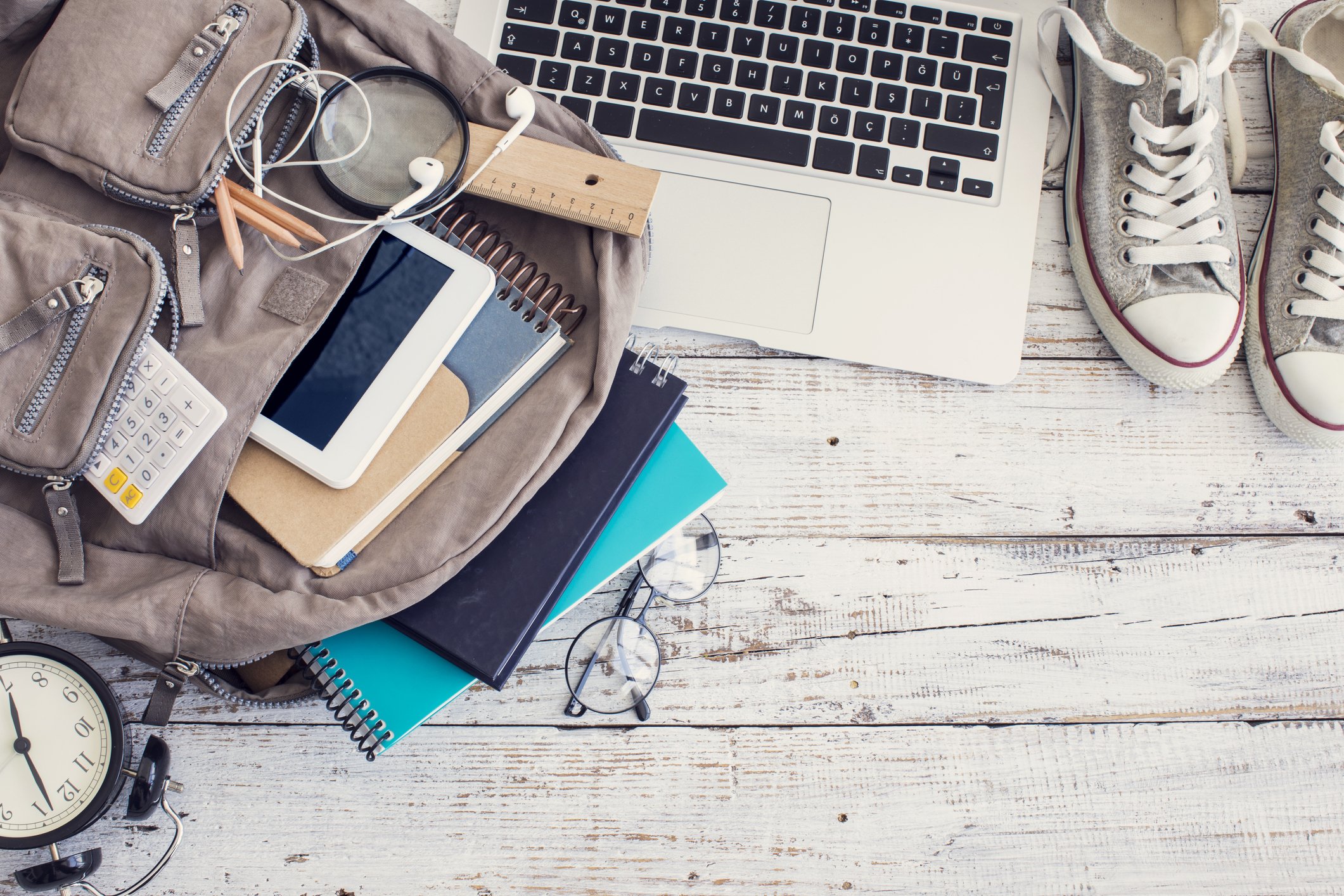 flat lay photograph of an open backpack with books, laptop, and sneakers