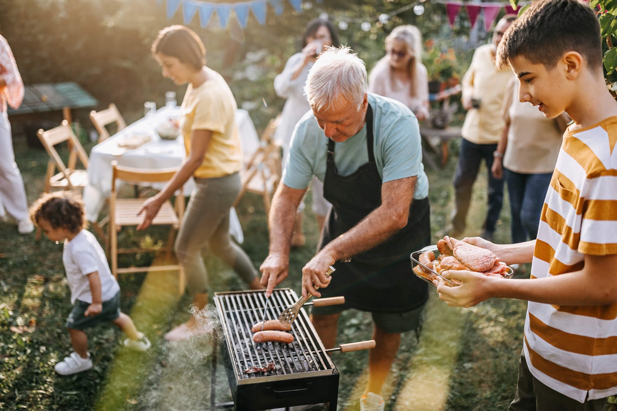 man and grandson grilling at an outdoor party