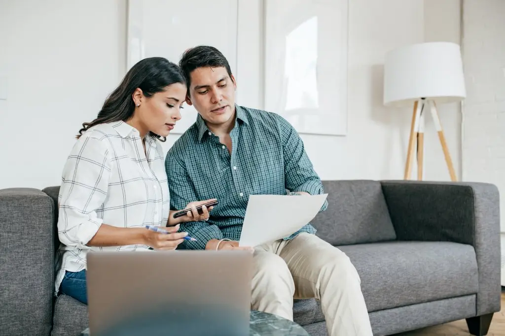 A couple sits on a couch while choosing a car insurance plan