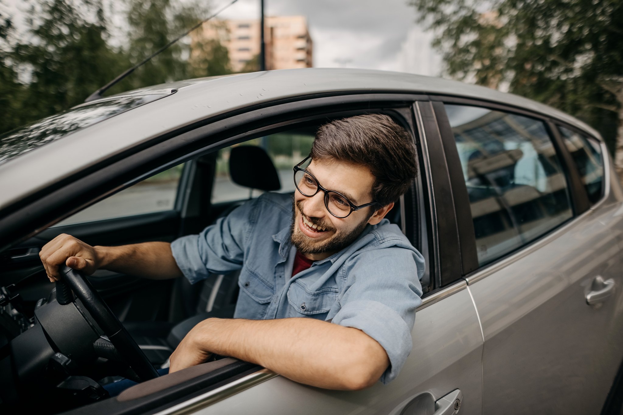 A man smiles as he leans out of his car window