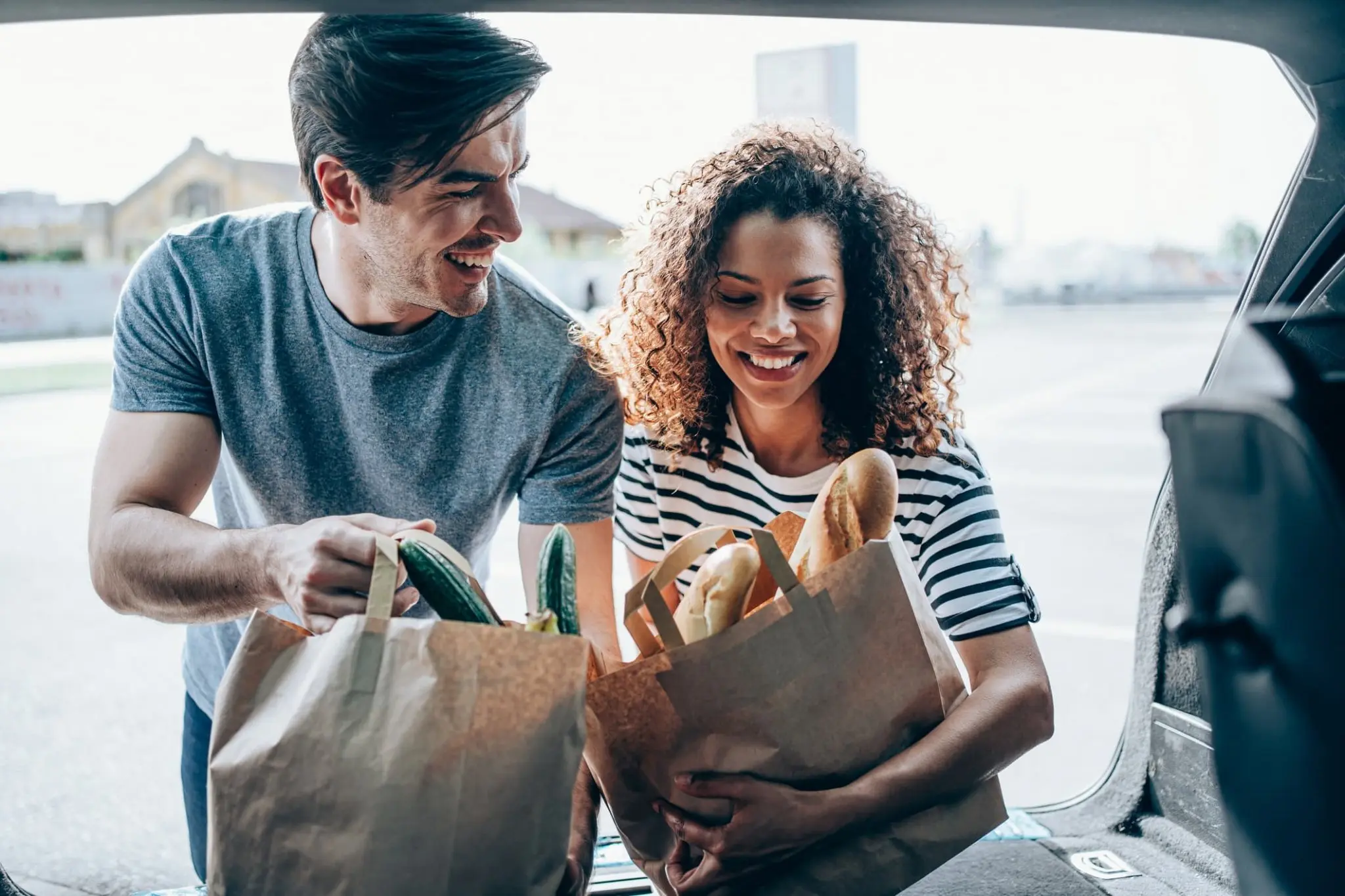 Young couple loading groceries into the trunk of their car.