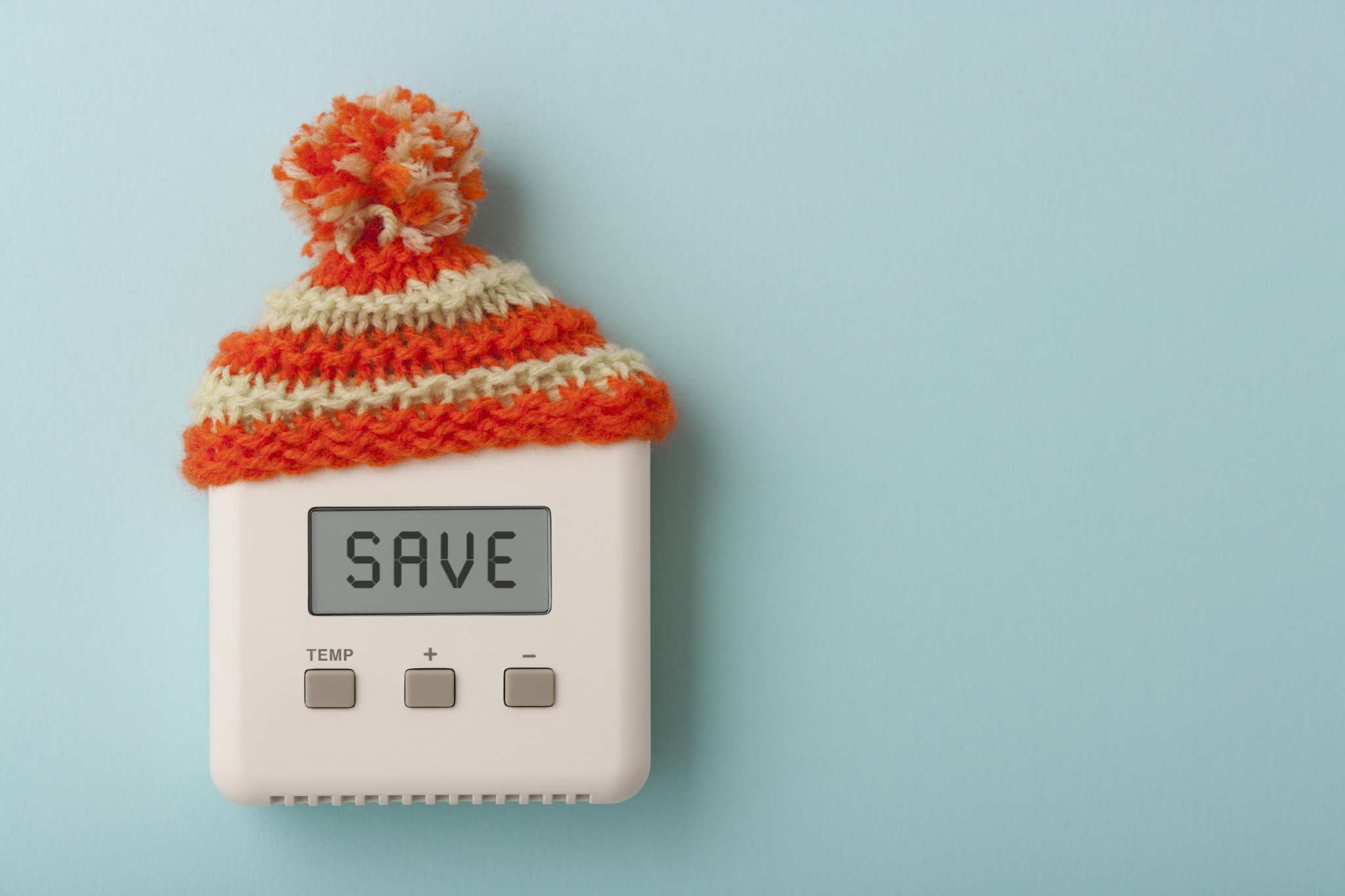 The word SAVE on a digital room thermostat wearing wooly hat.
