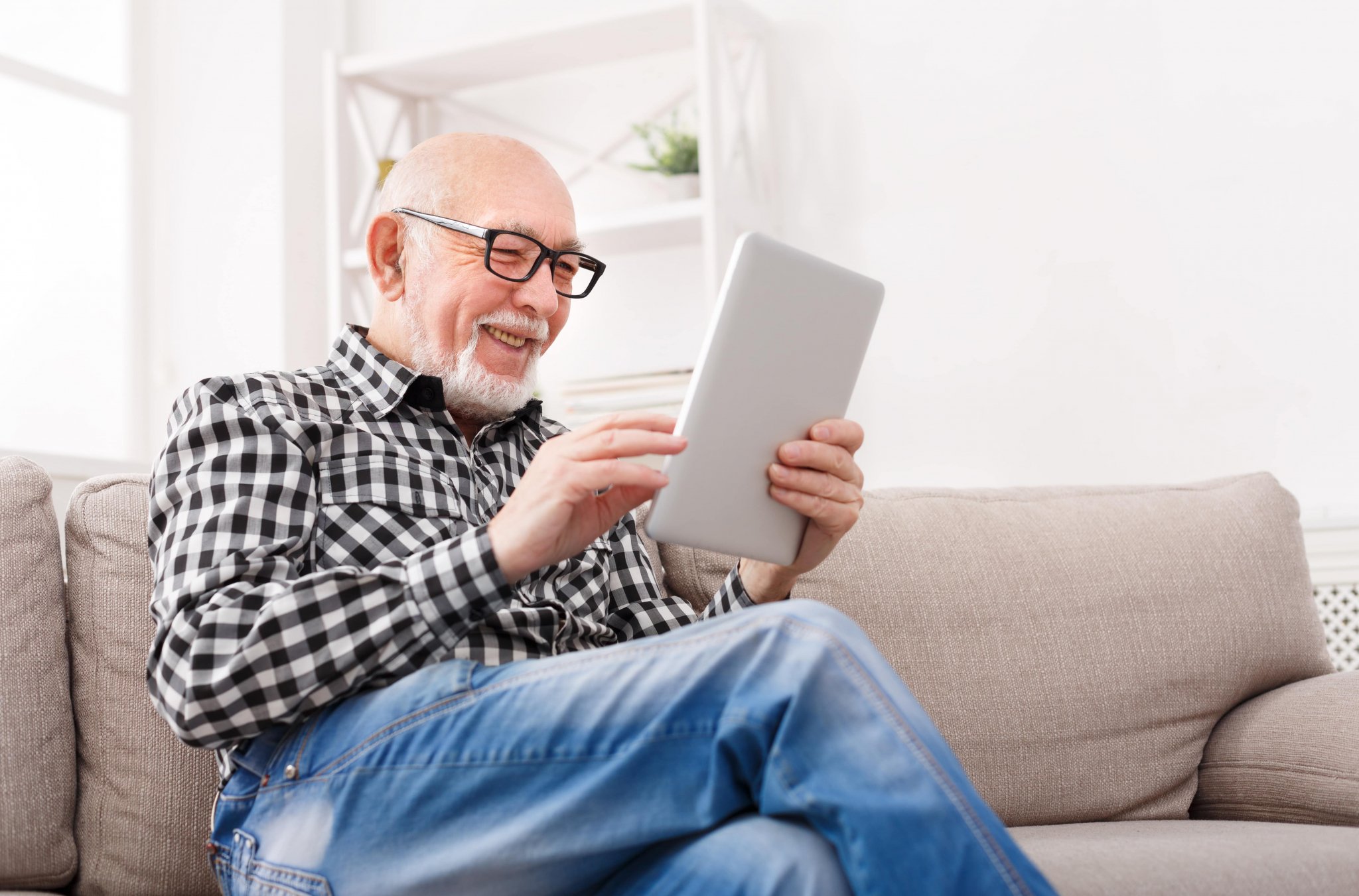 Older man using tablet on couch