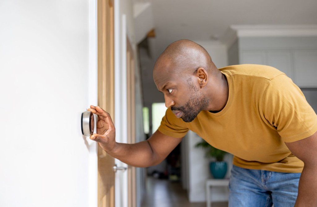 Person adjusting thermostat in their home.
