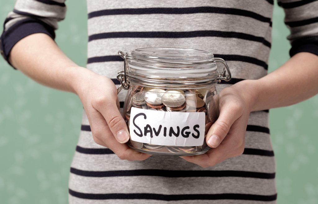 person holding savings in jar