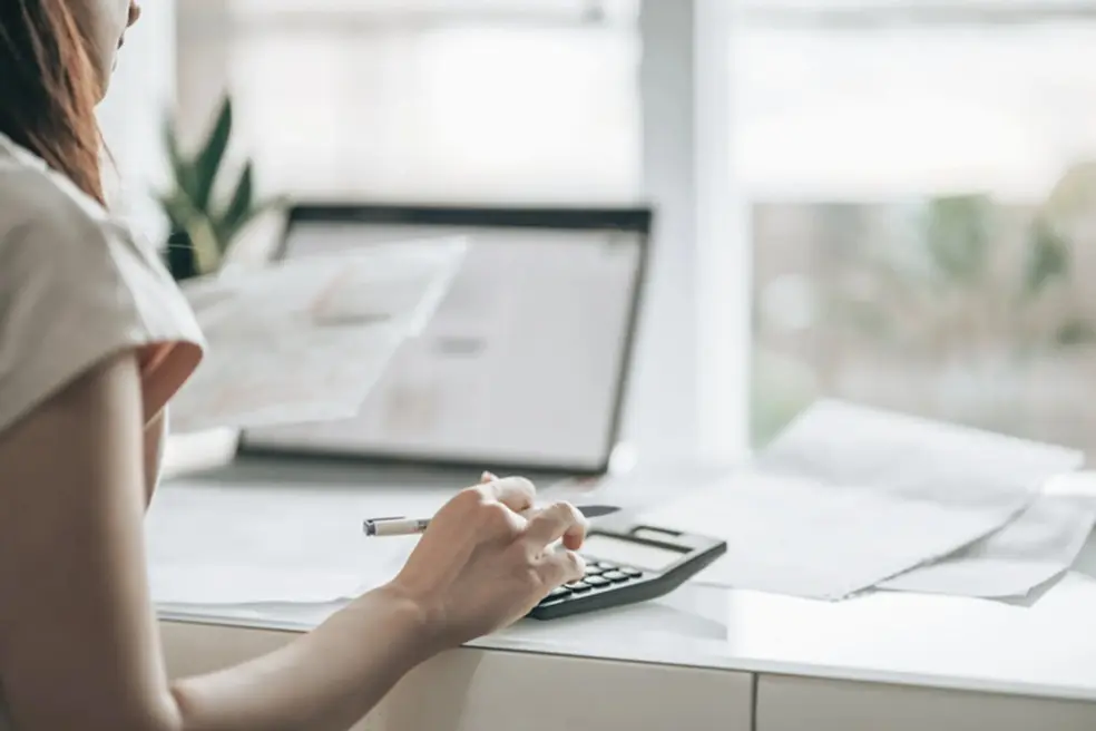 Woman calculating disposable vs. discretionary income while reviewing tax documents