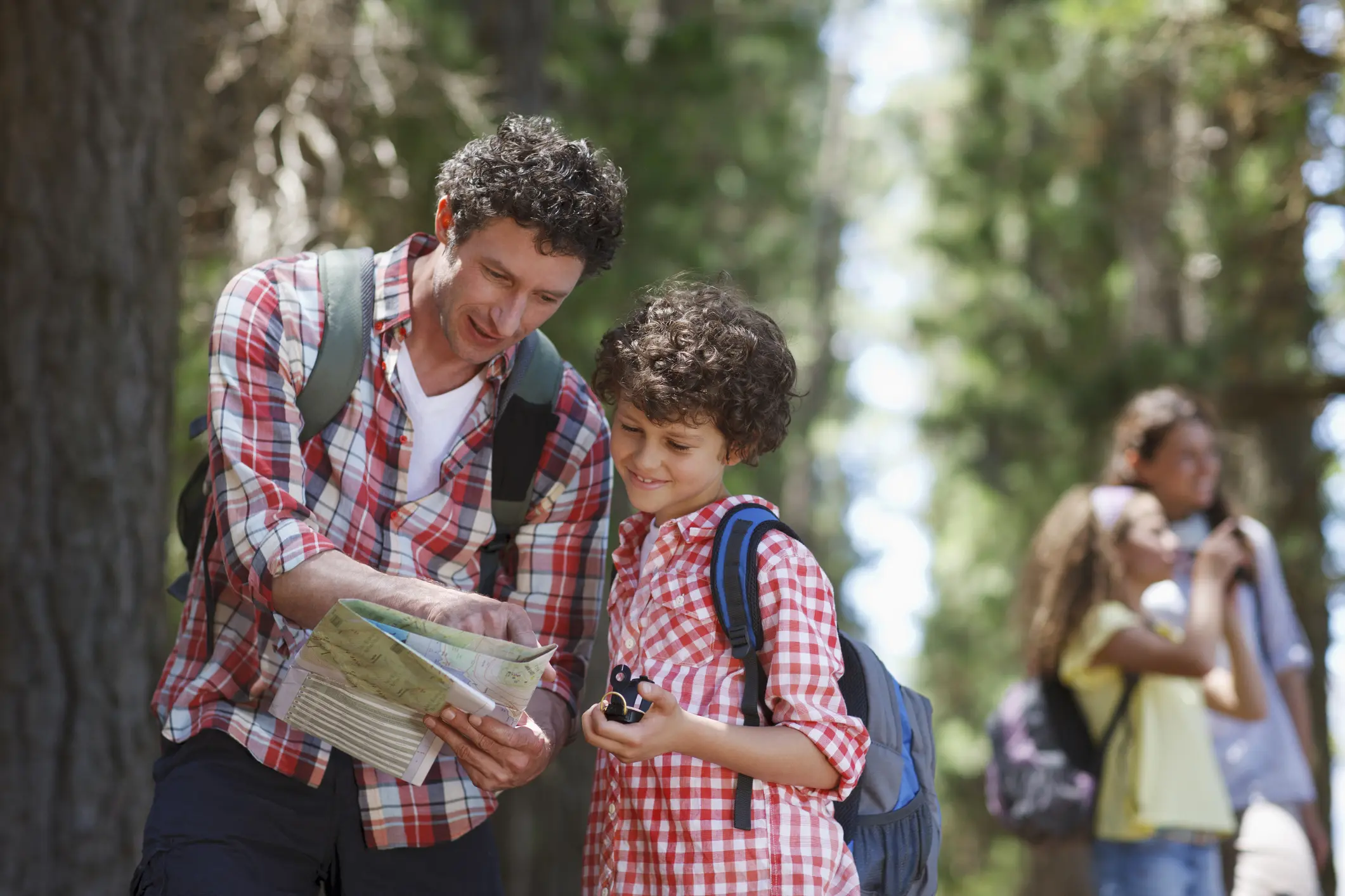 Father and son hiking with backpacks and looking at a map