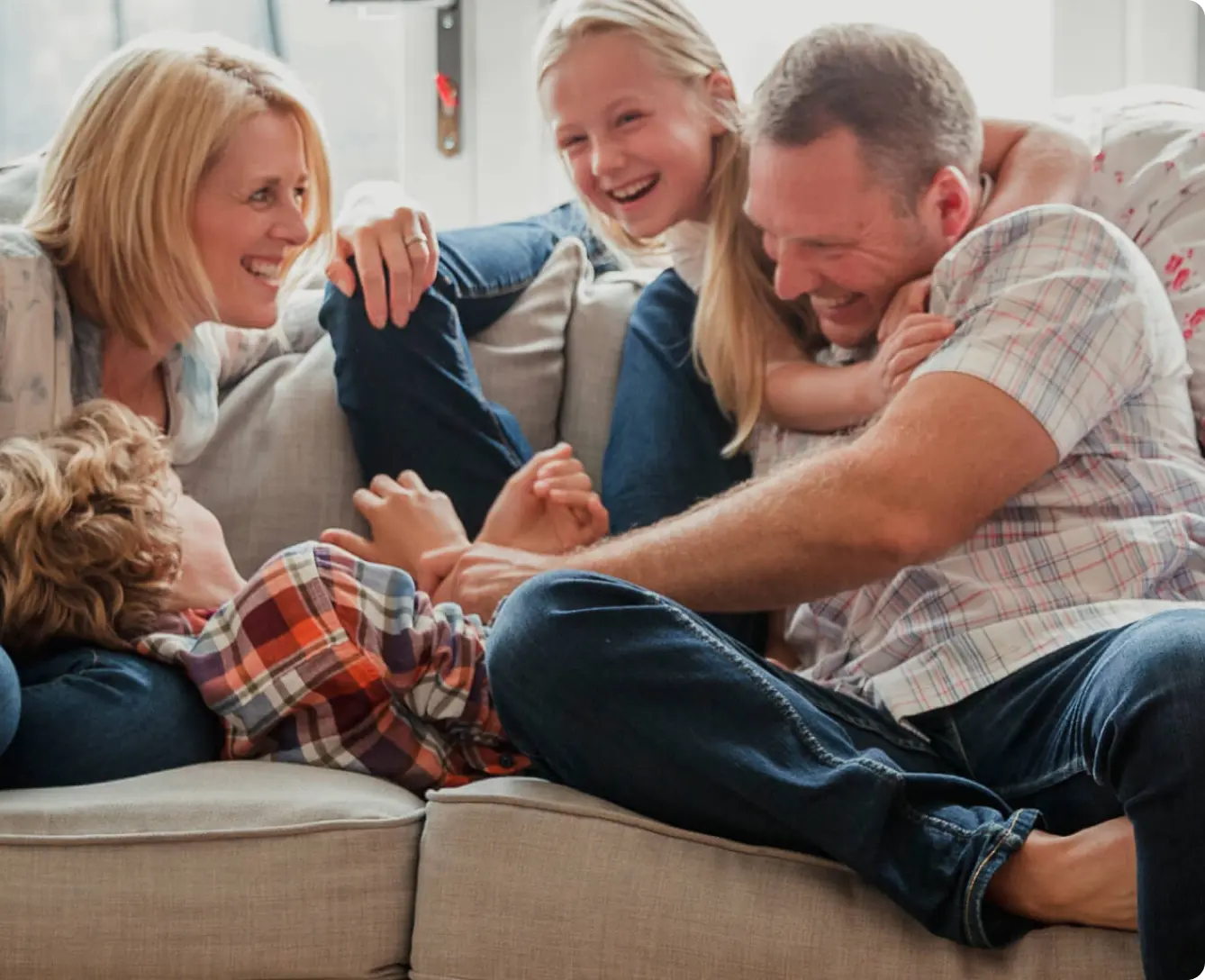 family playing and wrestling on couch