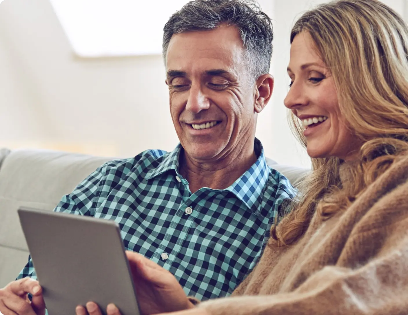 couple on couch smiling at tablet