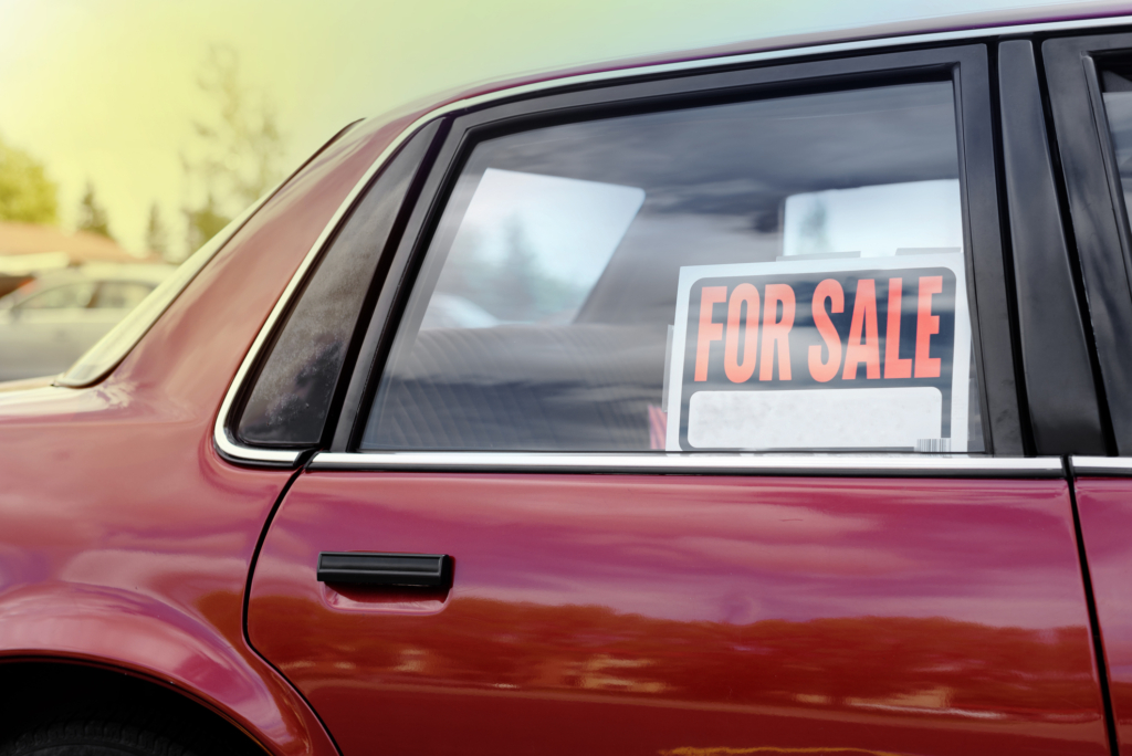 A used car with a “For Sale” sign posted in the back window.