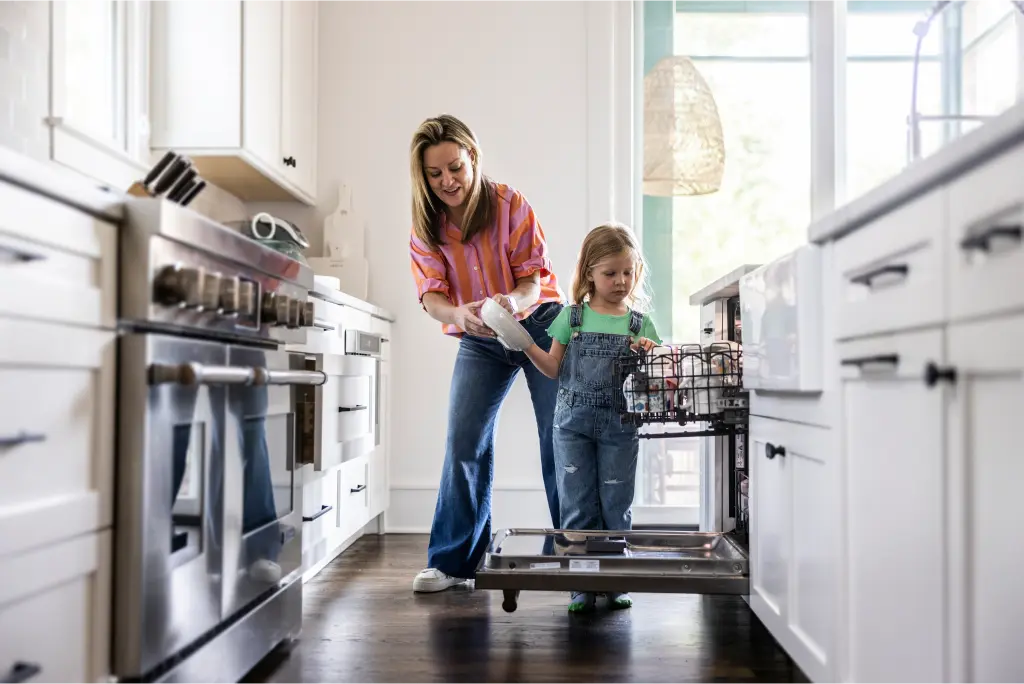Child and mother loading dishes into a newly financed dishwasher