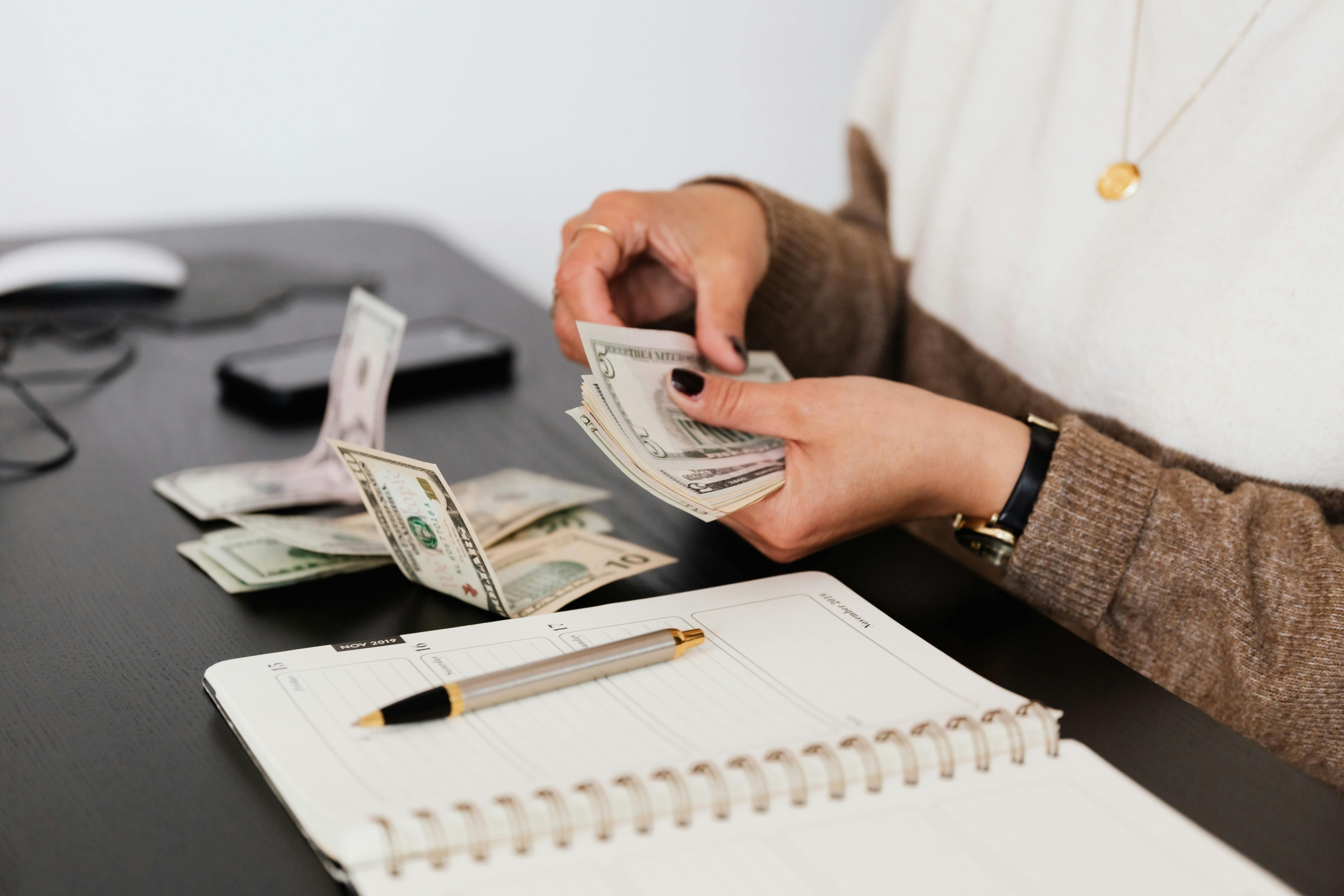 Person counting cash while planning a budget in a notebook