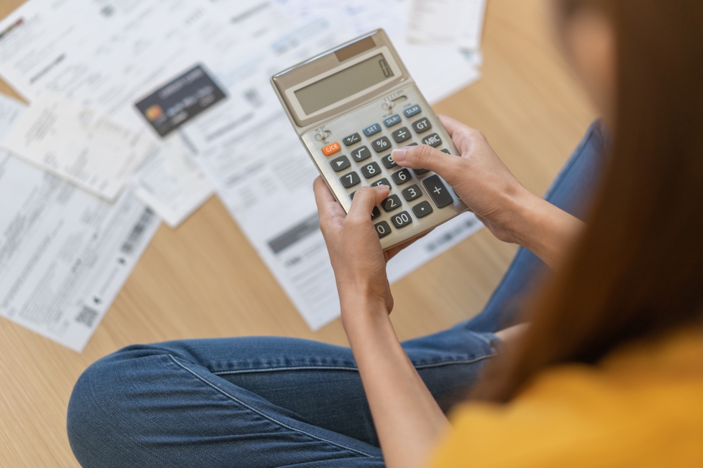A young woman holding a calculator trying to employ the debt snowball method.