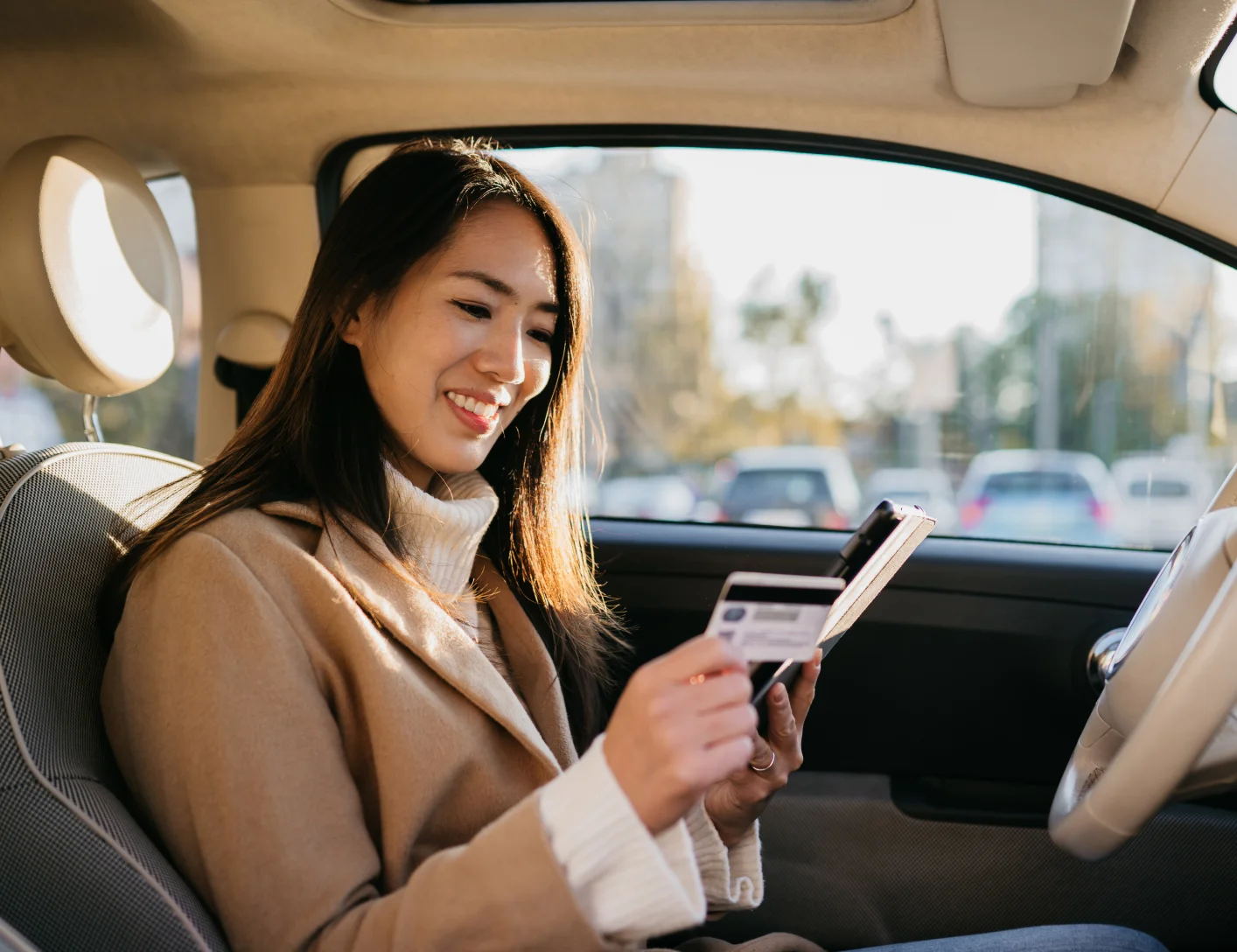 Woman in car and looking at credit cards